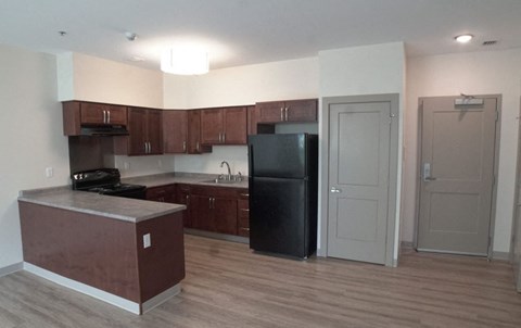 an empty kitchen with a black refrigerator and