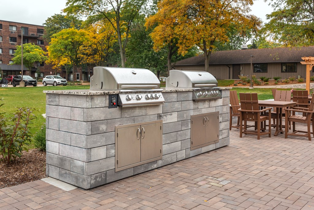 a outdoor kitchen with two grills and a table with chairs