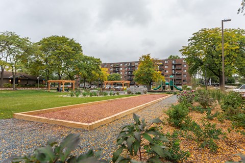 a garden with a gravel path and a playground in front of a building