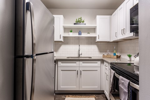 a kitchen with white cabinets and stainless steel appliances and a refrigerator