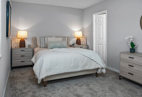 a bedroom with a bed and two night stands and a closet