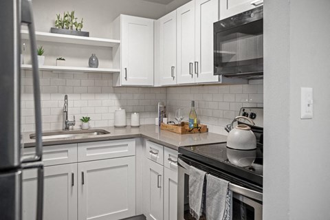 a kitchen with white cabinets and a stove and a sink