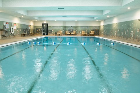 A large indoor swimming pool with a blue tinted water.
