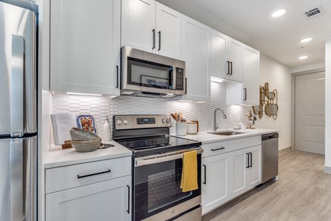 a white kitchen with stainless steel appliances and white cabinets