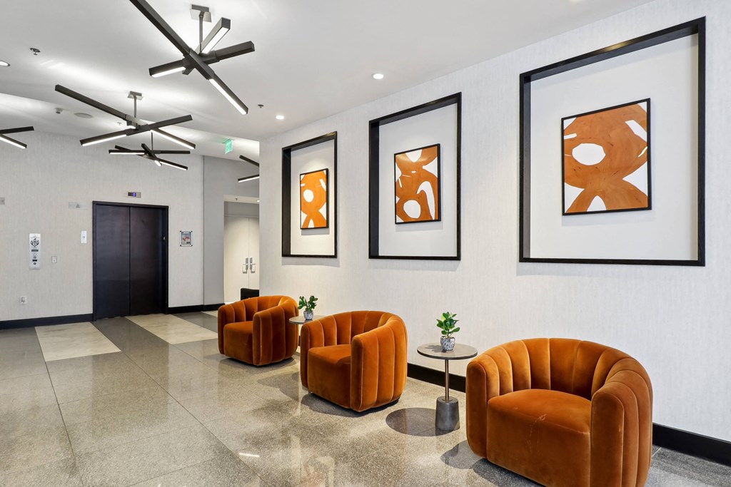 a lobby with orange chairs and pictures on the wall at The Zenith, Baltimore, Maryland