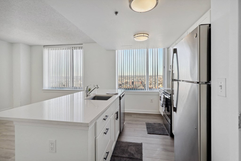 a white kitchen with a large window and a stainless steel refrigerator at The Zenith, Maryland