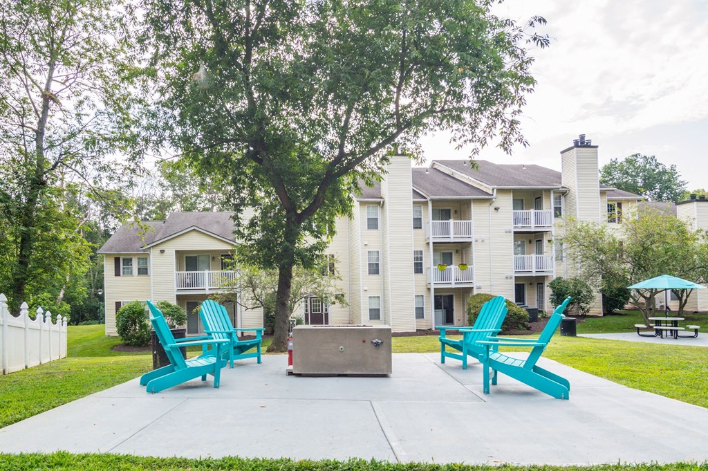 a fire pit and lounge chairs sit on a concrete patio in front of an apartment building at Hamilton at Kings Place, Maryland, 21046