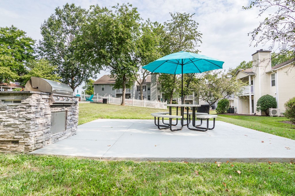 a patio with a table and umbrella and a grill at Hamilton at Kings Place, Maryland
