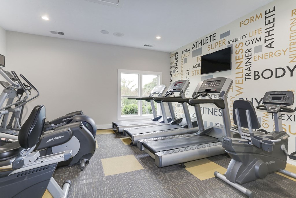 a gym with four treadmills and a television at Madison at Eden Brook, Columbia