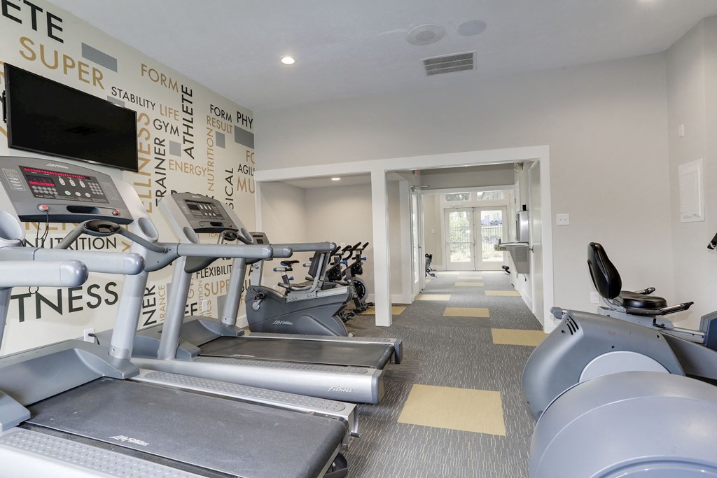 a gym with cardio equipment and a wall of black and white graffiti at Madison at Eden Brook, Columbia Maryland
