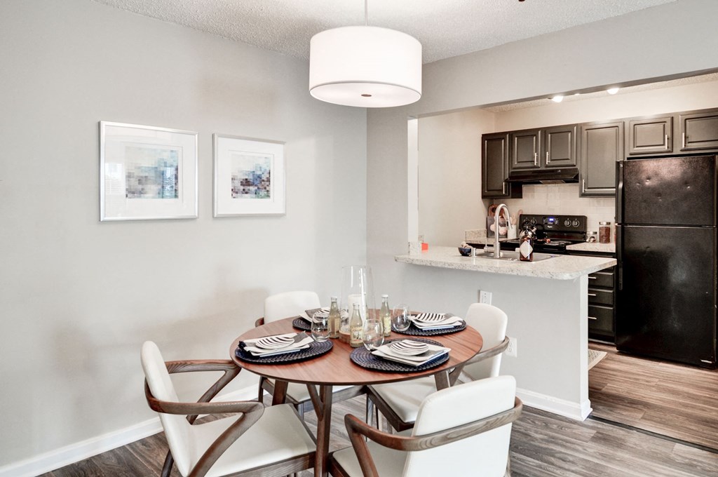 a dining area with a table and chairs and a kitchen in the background at Hamilton at Kings Place, Columbia Maryland