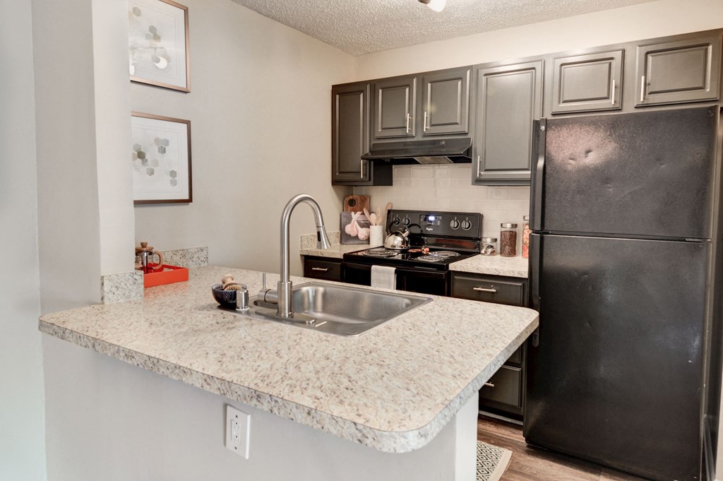 a kitchen with granite countertops and black appliances at Hamilton at Kings Place, Columbia, MD
