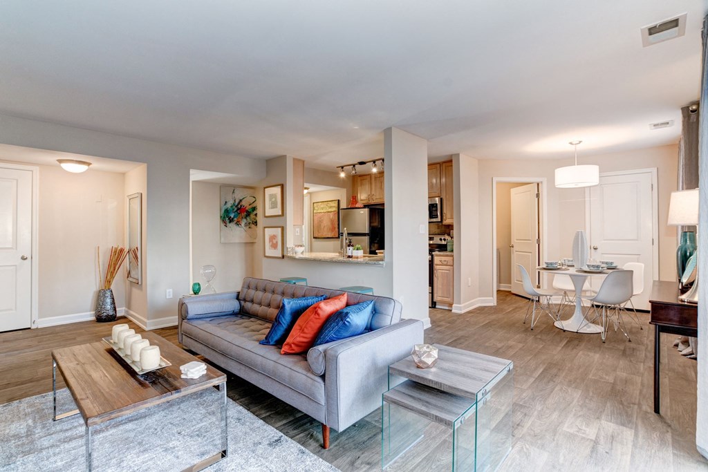 a living room with a couch table and chairs and a kitchen in the background at Ellicott Grove, Ellicott City