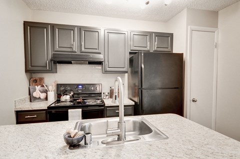 a kitchen with gray cabinets and white countertops