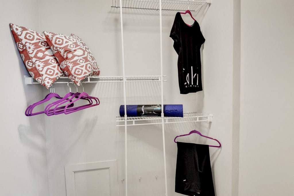 a rack for clothes and shoes hangs on the wall in a small room at Hamilton at Kings Place, Columbia, MD