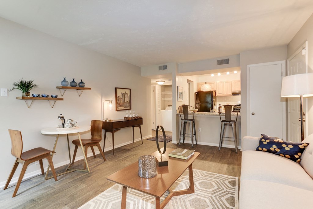 a living room with a couch a table and a chair and a kitchen in the background at Madison at Eden Brook, Columbia