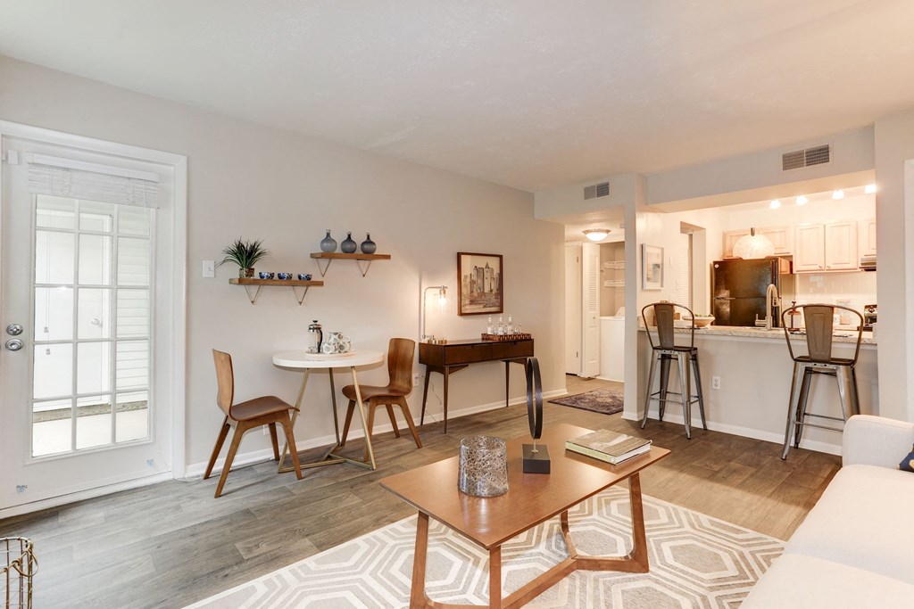 a living room with a couch a table and chairs and a kitchen in the background at Madison at Eden Brook, Columbia Maryland