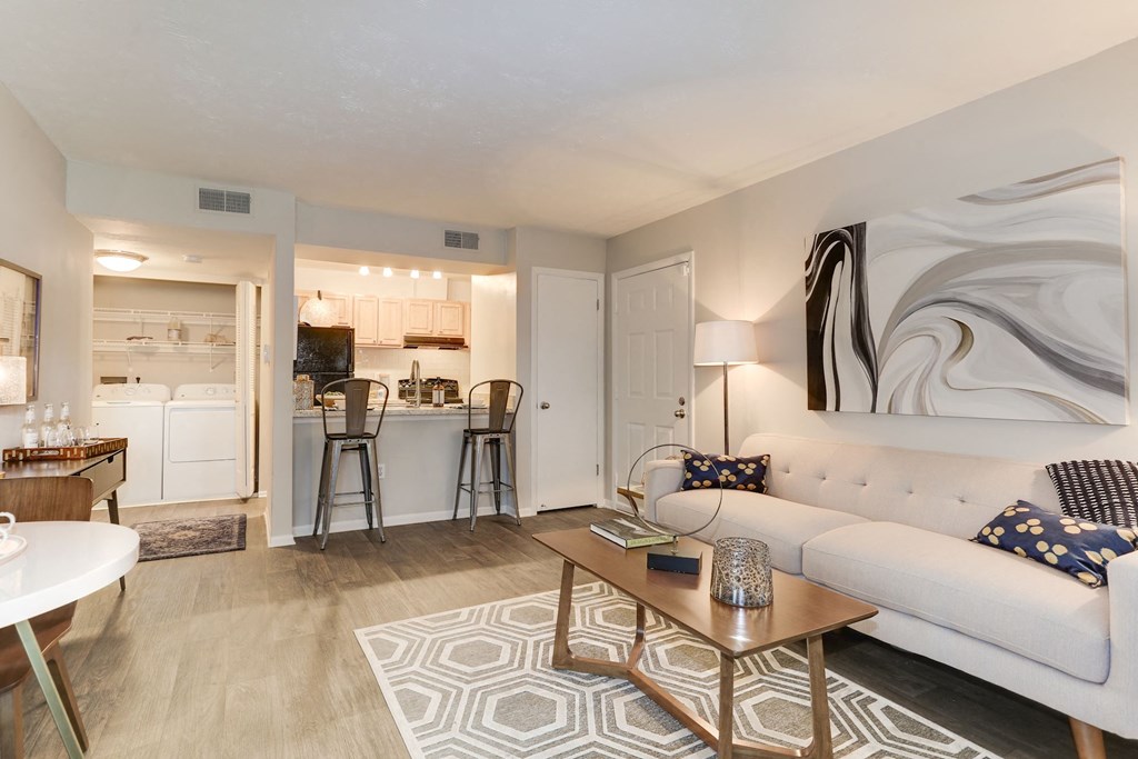 a living room with a couch coffee table and a kitchen in the background at Madison at Eden Brook, Columbia, 21046