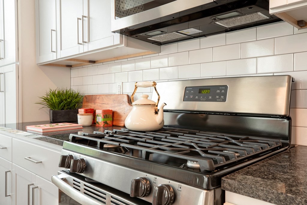 The Refinery kitchen with white cabinets and a stainless steel stove