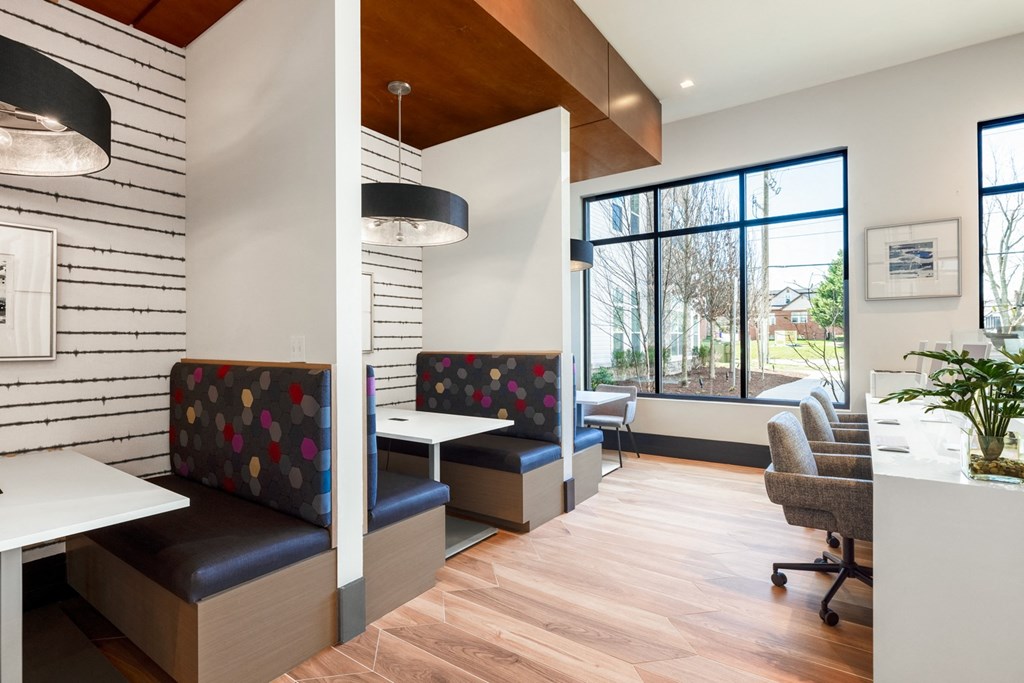 a lounge area with tables and chairs and a large window