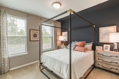 a bedroom with a large bed and two windows