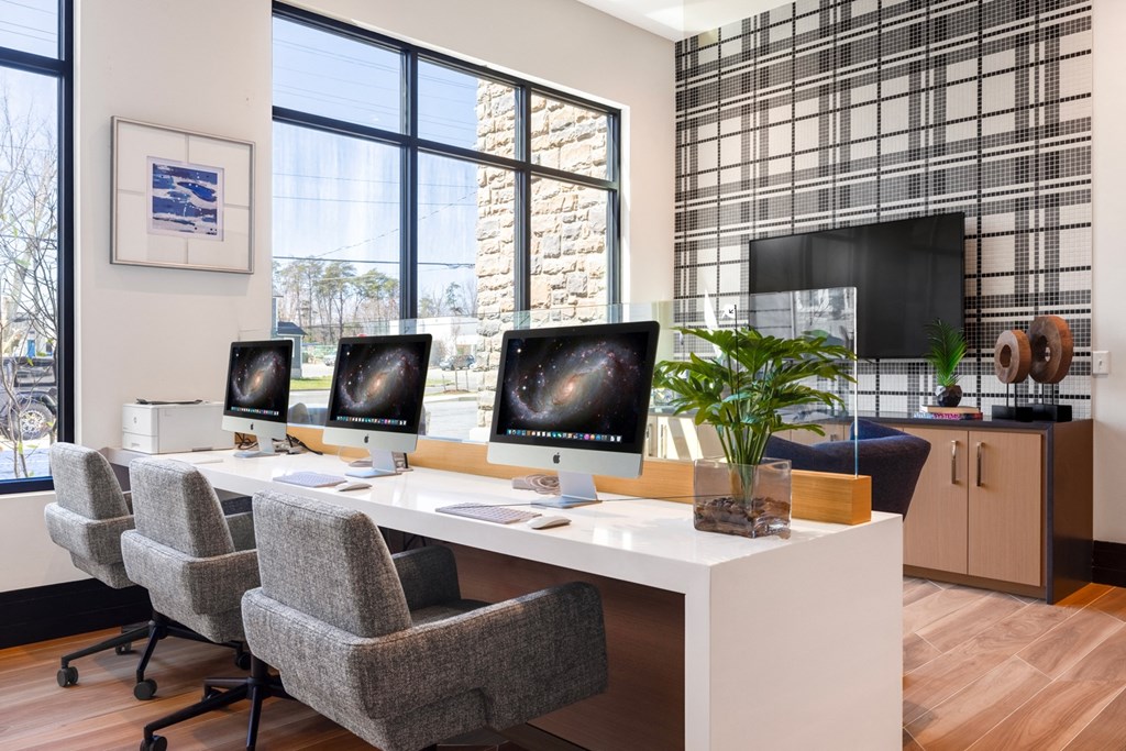 a desk with three computer monitors and chairs in an office