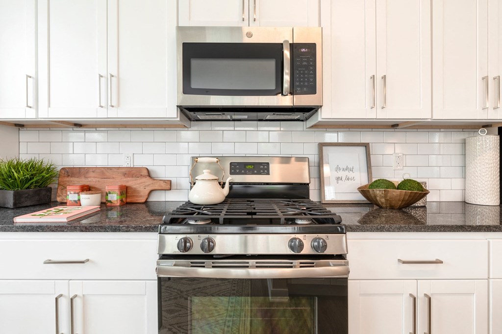 The Refinery kitchen with white cabinets and a stainless steel stove