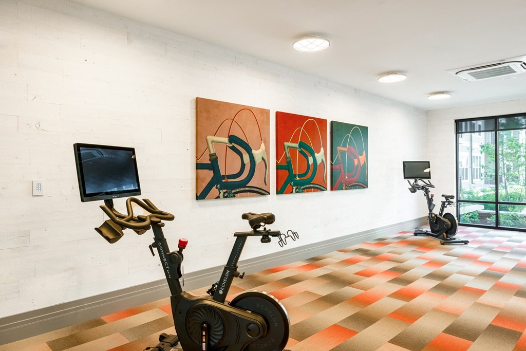 a room with two exercise bikes and three paintings on the wall