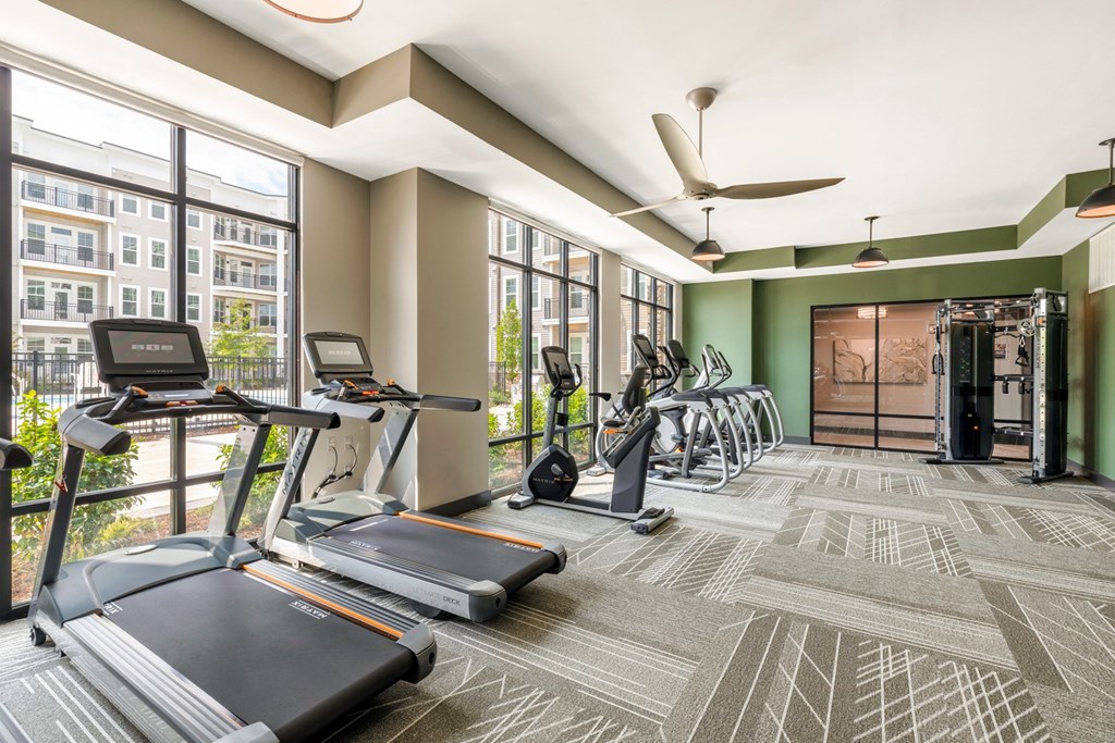 a gym with treadmills and other exercise equipment in a room with large windows