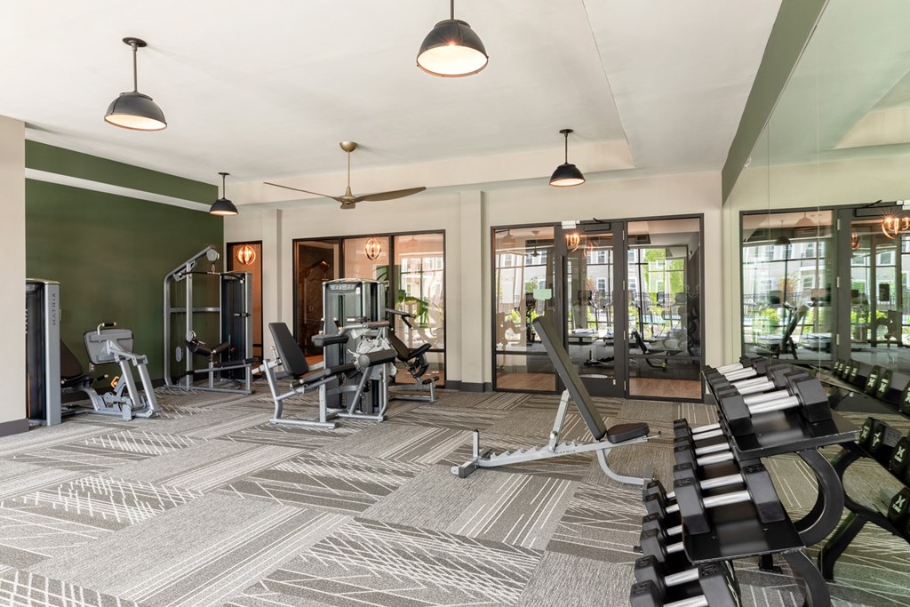 a gym with cardio machines and weights in a room with glass doors