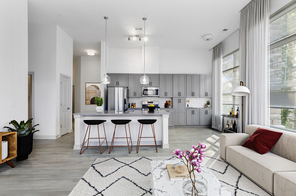 The Forge living room with a white couch and a white coffee table with three stools in front