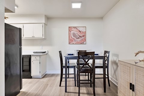 A kitchen with a table and chairs and a fridge.