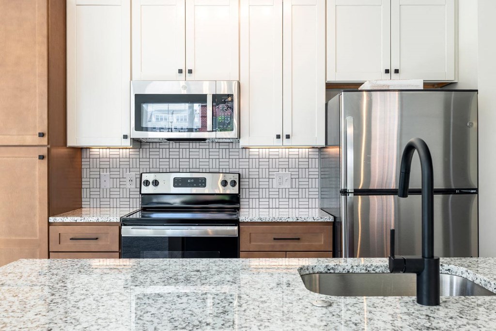 a kitchen with white cabinets and black appliances