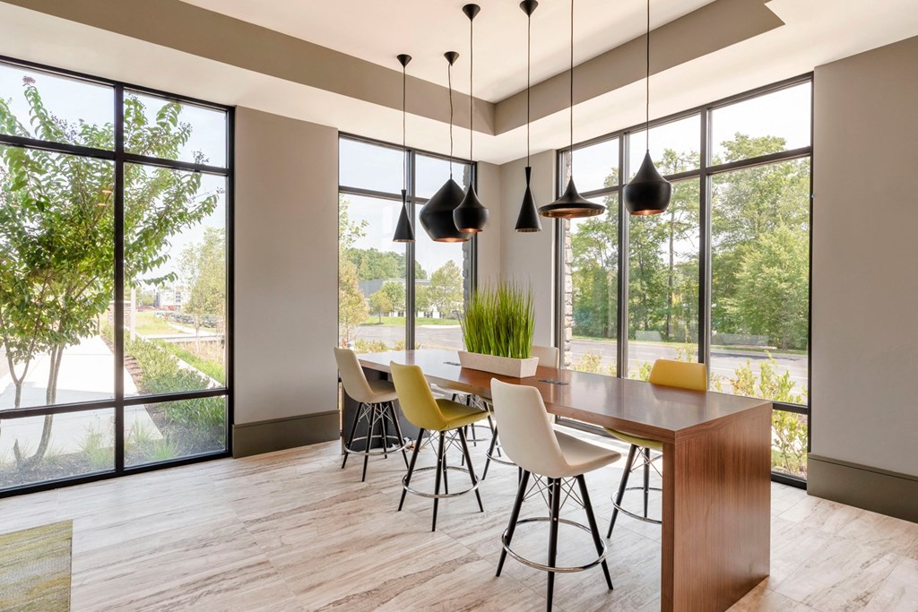 a dining room with large windows and a wooden table and chairs