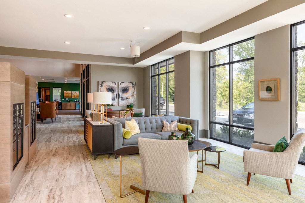 a living room with a couch and chairs and large windows