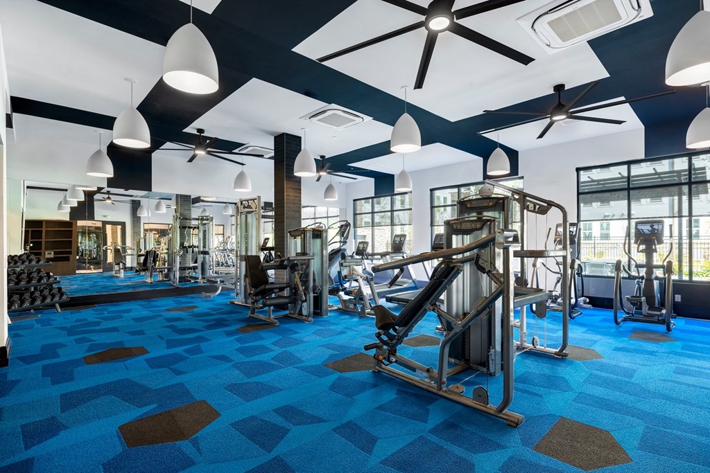 a gym with weights machines and lights on the ceiling