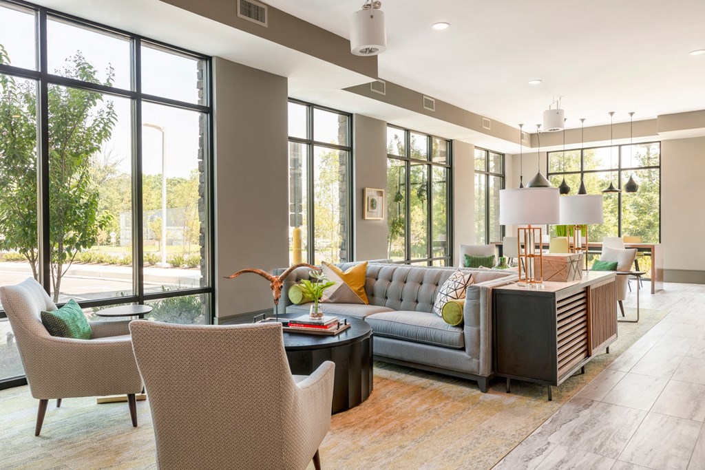 a living room with couches and chairs and large windows