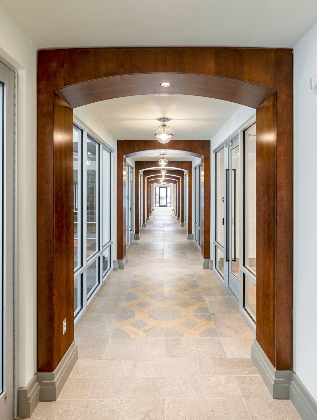 a view down a hallway with a large wood archway and a tiled floor
