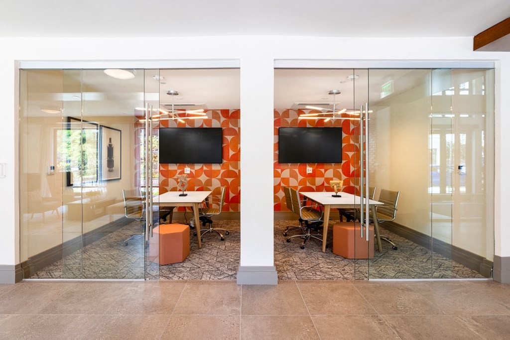 a conference room with orange accent wall and glass doors