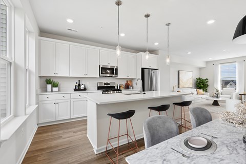 A modern kitchen with a marble table and bar stools.