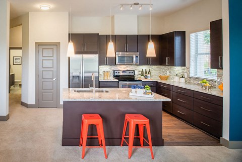 a modern kitchen with orange stools in front of a counter