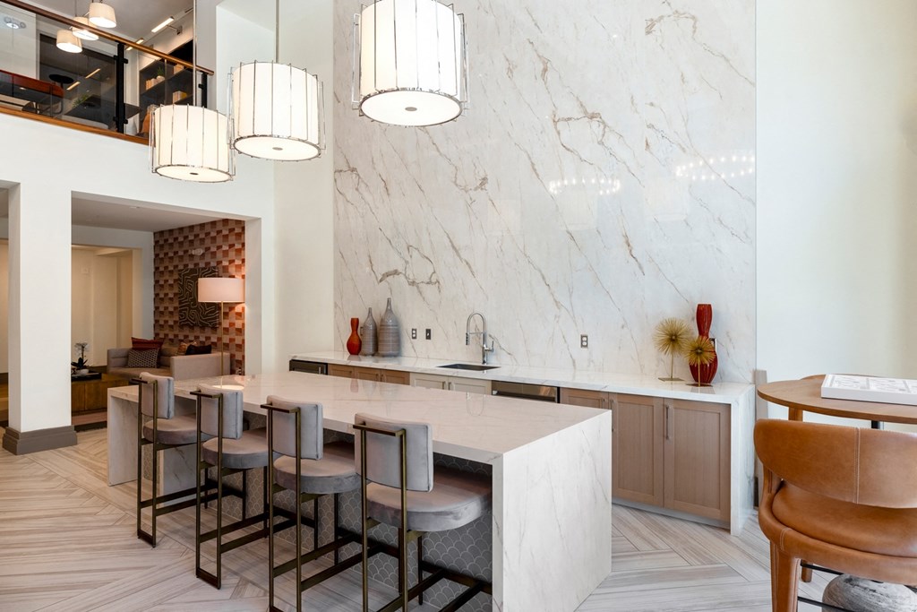 a kitchen with white marble countertops and a long island with a sink and a row of