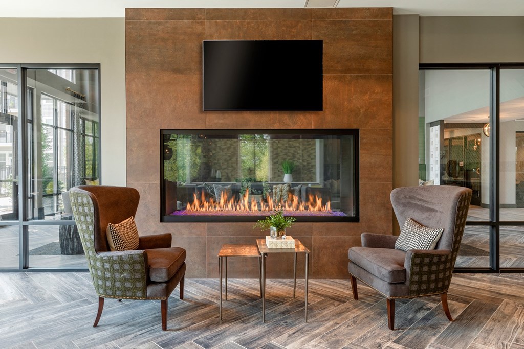 a living room with two chairs and a fireplace with a tv above it