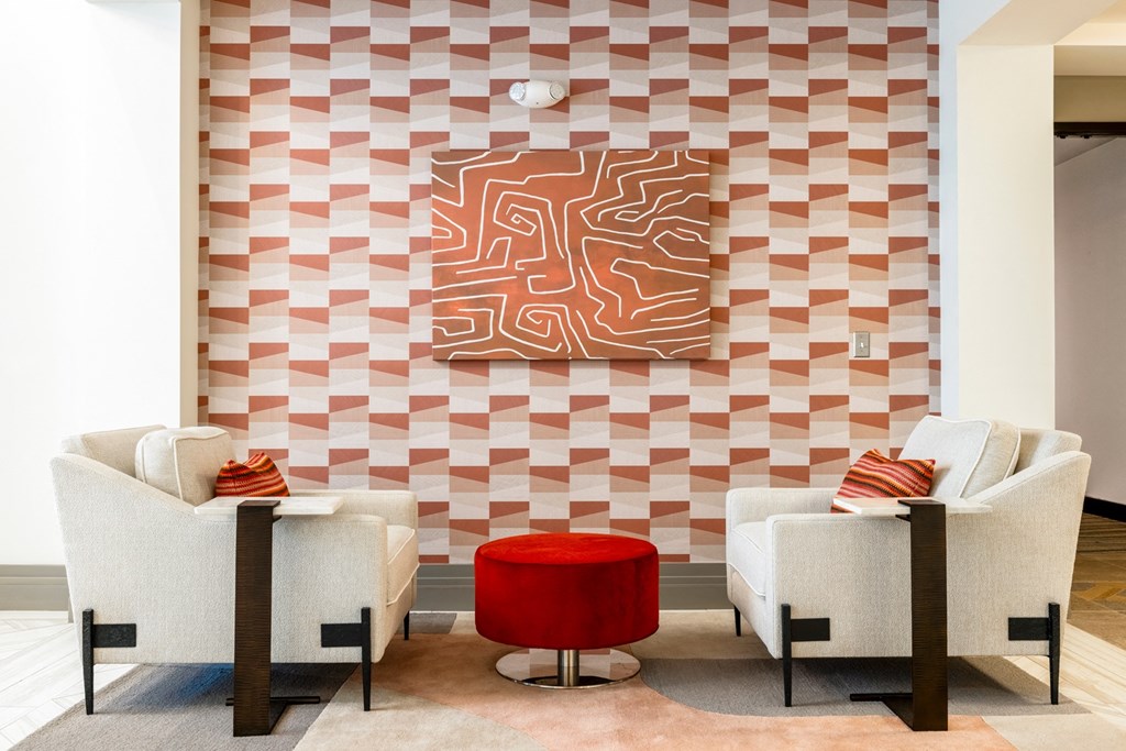 a living room with two white chairs and a red ottoman in front of a geometric