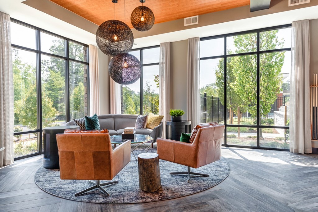 a living room with couches and chairs and large windows