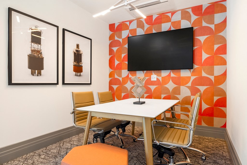 a meeting room with a table and chairs and a television on the wall