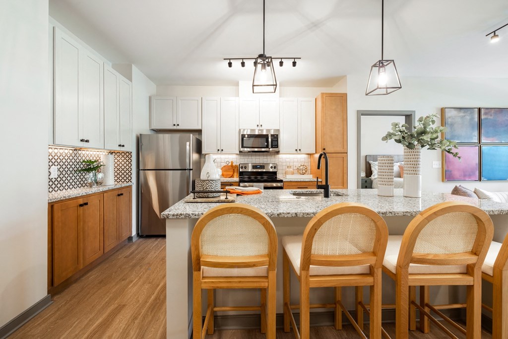 a kitchen with white cabinets and a large island with four wooden chairs