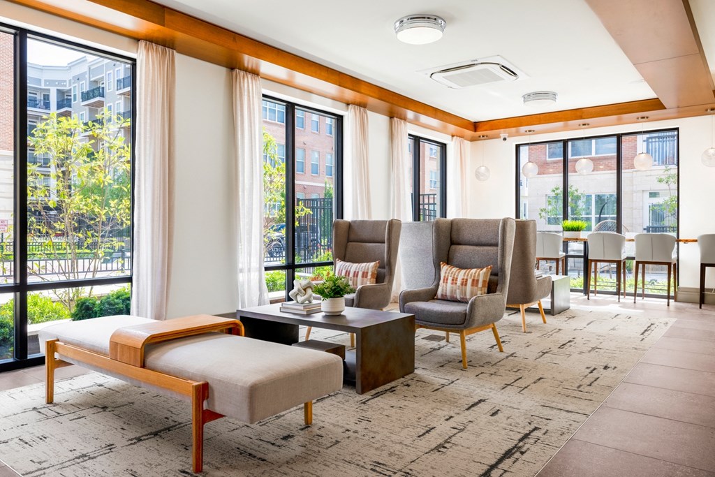 a seating area with chairs and a coffee table in a room with large windows