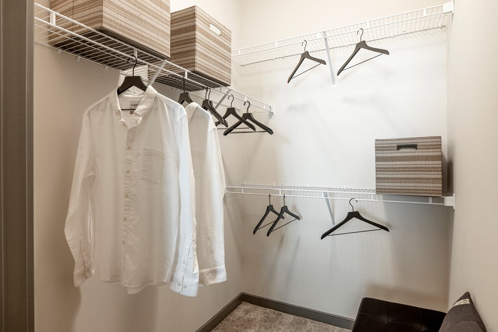a walk in closet with a white shirt and black hangers