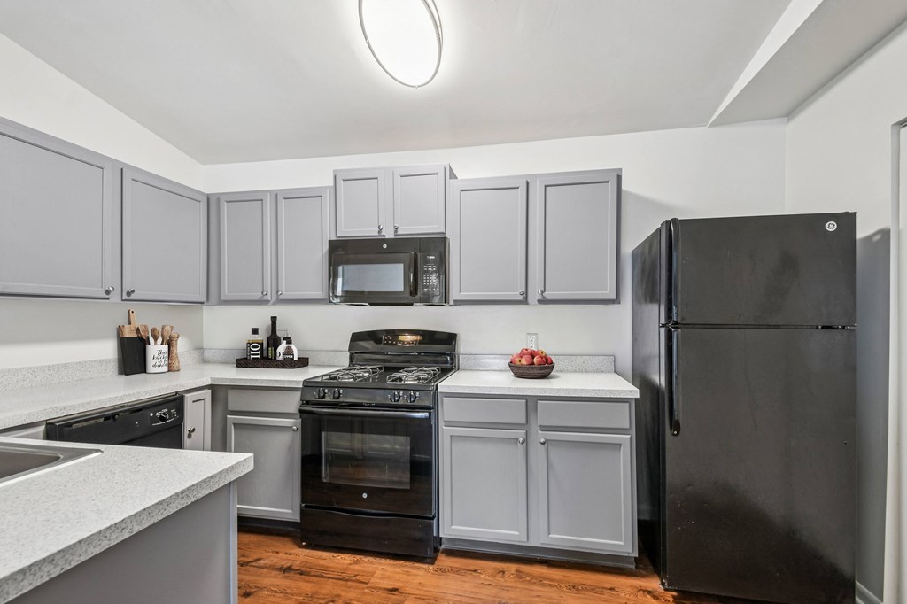 A kitchen with a black refrigerator and a stove with a pot on it.